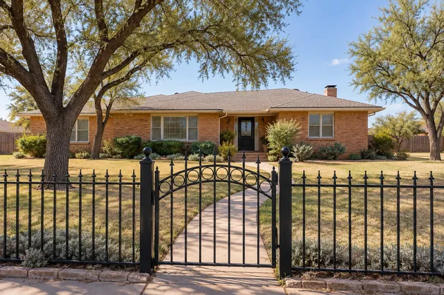 A 4 ft ornamental fence that frames a brick home without hiding it.