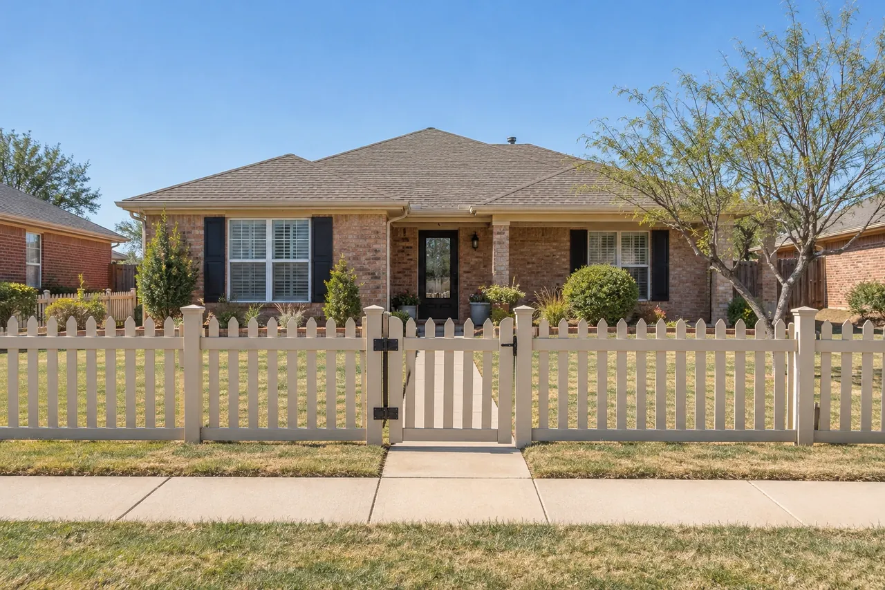 Tan vinyl picket fence in front of a Lubbock brick home