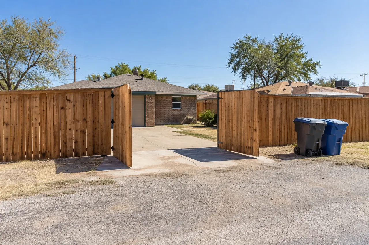 Cedar privacy fence with a wide gate opening onto a Lubbock alley